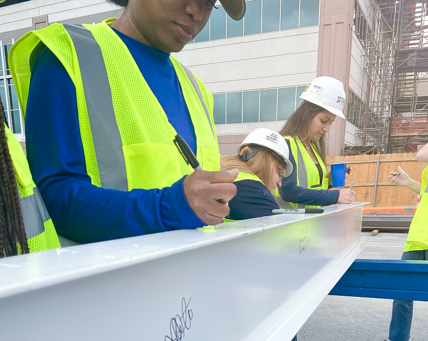 Female construction workers signing a steel beam at HCA St. David's North Austin Medical Center