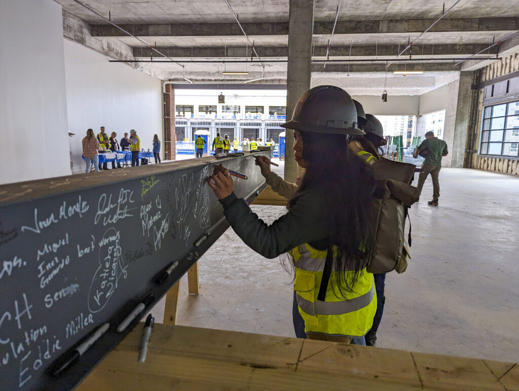A female construction worker signs a steel beam on a construction jobsite