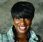 Woman with a bright smile wearing a gray jacket and black top, embodies WEBMyers Construction's success story with her stylish haircut and earrings.