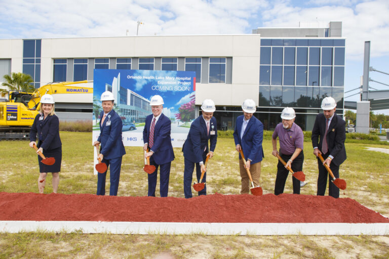 Group of individuals in hard hats at a groundbreaking ceremony for the Brasfield & Gorrie construction of the new Orlando Health Lake Mary Hospital facility.