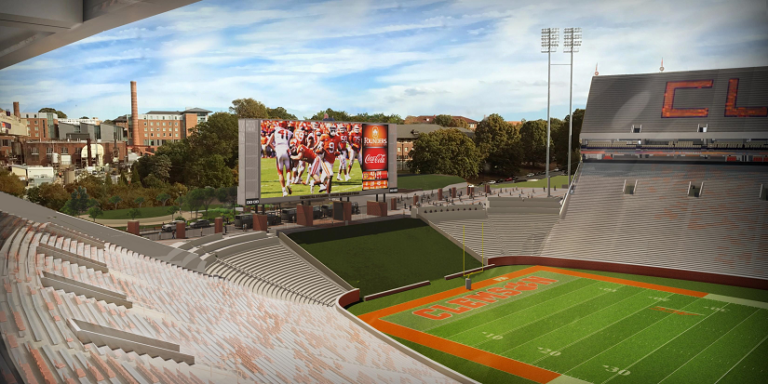 A panoramic view of an empty Memorial Stadium at Clemson University on a clear day, with the scoreboard displaying a moment from a game.