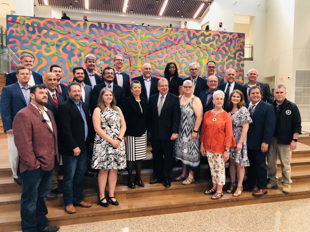 A group of professionals posing for a photo in front of a vibrant, abstract mural, symbolizing Building for the Future.