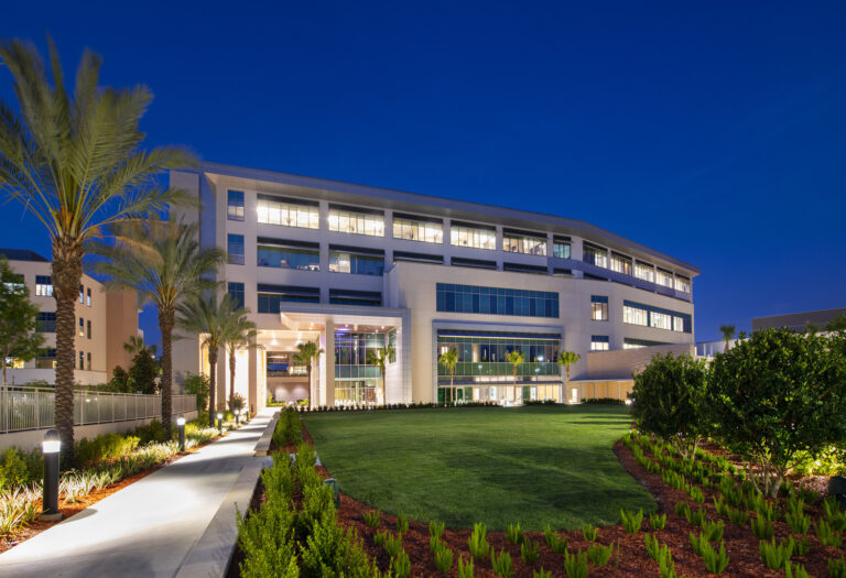 Modern office building illuminated at dusk with landscaped pathway and palm trees, constructed by Brasfield & Gorrie, a general contractor.