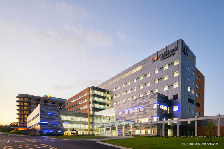 Modern hospital complex with multiple connected buildings, large windows, and illuminated signage, photographed at sunset under a clear sky—a signature project by Brasfield and Gorrie near the Jackson Office.