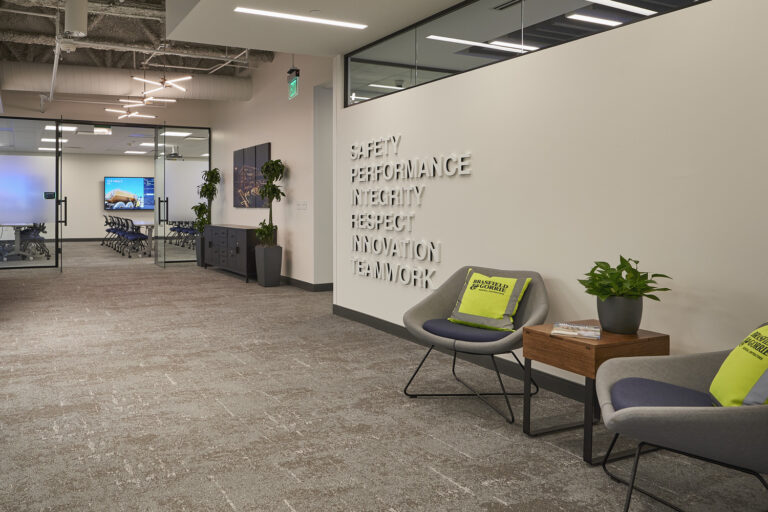 Zona de recepción de la oficina de Brasfield and Gorrie en Charlotte, con una pared en la que se muestran los valores de la empresa y dos sillas con cojines con el logotipo de la marca.