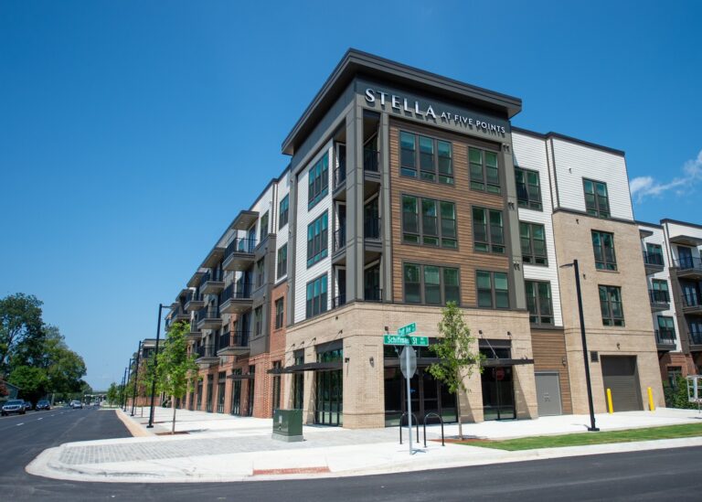 A modern four-story apartment building with balconies, labeled 