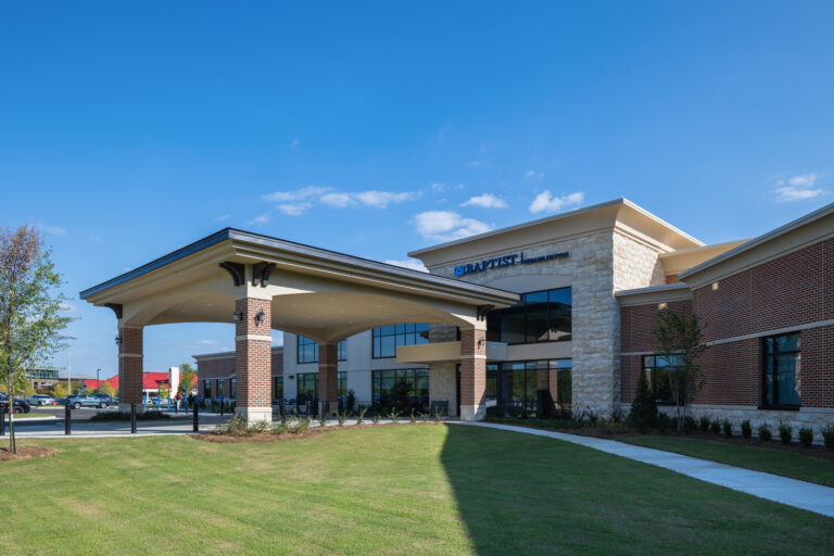A modern brick and stone Jackson Office by Brasfield and Gorrie, featuring large windows, a covered entrance, and a landscaped lawn under a clear blue sky.
