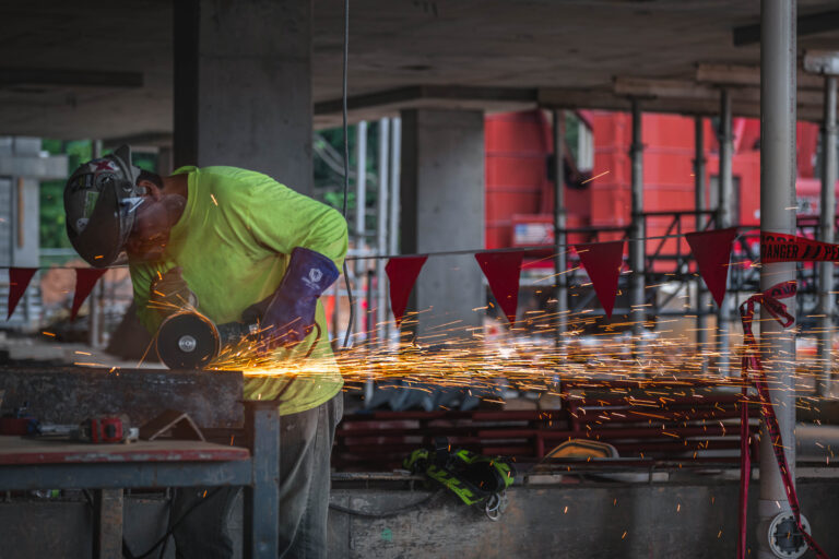 Construction worker using an angle grinder, creating sparks at a construction site.