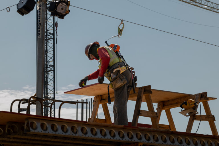 Construction worker making measurements at a building site.