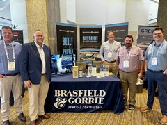 Five men standing behind a Brasfield & Gorrie Nashville office display table at a conference.