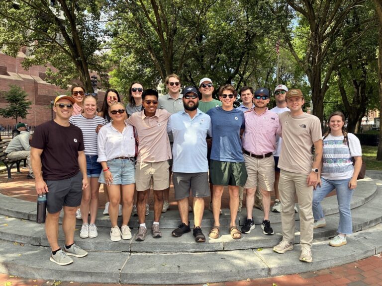 A large group of young adults from the Nashville office of Brasfield and Gorrie posing for a photo outdoors on a stone plaza.
