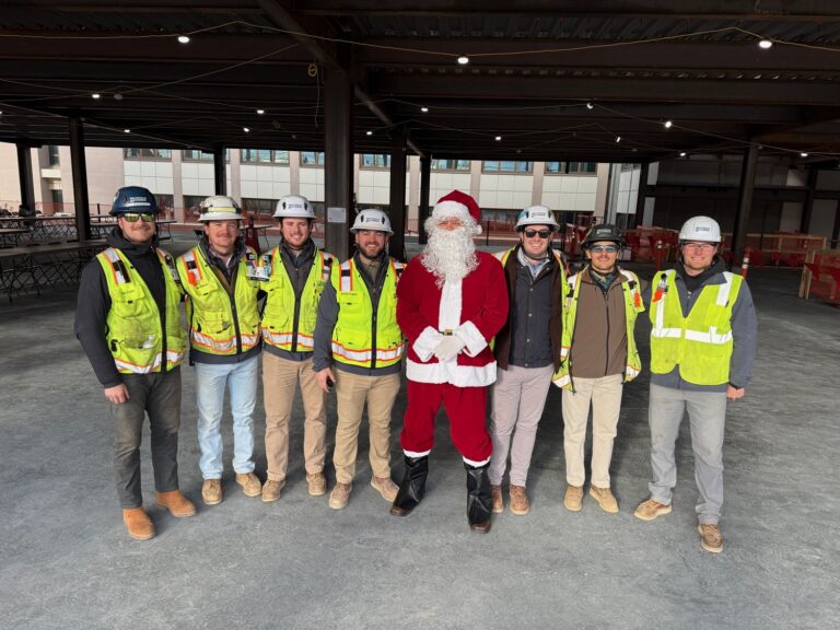 Santa Claus stands with eight Brasfield and Gorrie construction workers in hard hats and high-visibility vests at a Nashville office building site.