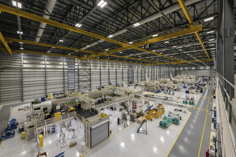 El interior de una gran fábrica con muchas máquinas ensamblando aviones.