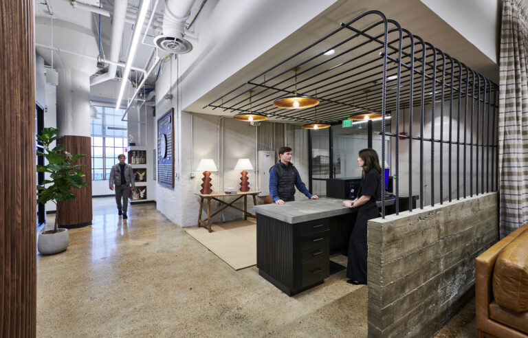 Two individuals conversing at a table in a modern office.