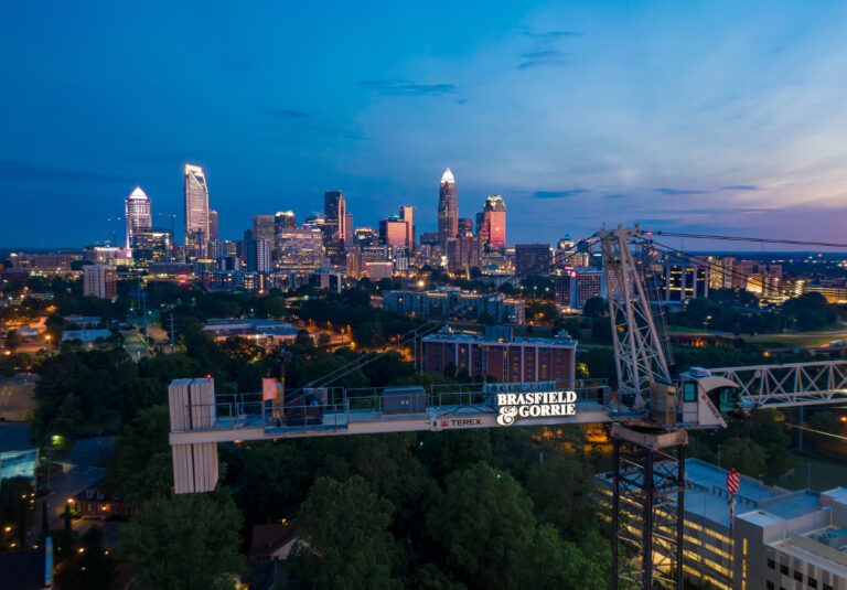 Twilight view of a city skyline with illuminated buildings and a construction crane in the foreground, perfect for home decor inspiration.