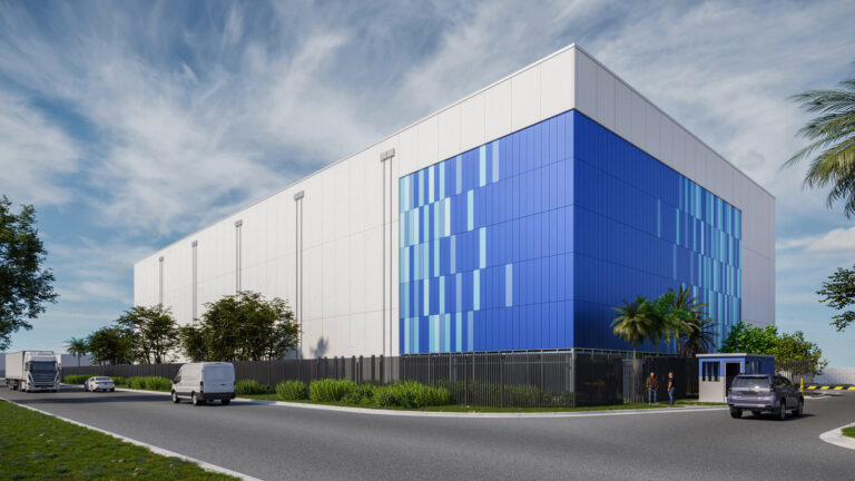 A modern, large blue and white industrial building houses Advanced Project Solutions, with vehicles parked nearby and people standing near the entrance on a clear day.