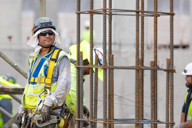 Unos trabajadores de la construcción, equipados con material de seguridad, posan junto a una estructura de barras de refuerzo en una obra al aire libre, lo que pone de manifiesto la ventaja competitiva de Brasfield and Gorrie en materia de seguridad y ejecución de proyectos.