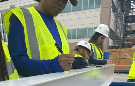 Female construction workers signing a steel beam