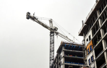 A crane stretches over an office building under construction