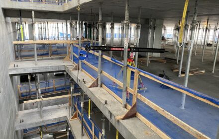 A camera boom holds a laser scanner in open space on an interior construction site