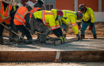 Construction workers collaborating to smooth concrete