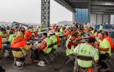 Construction workers gather around a table during a party on a construction site